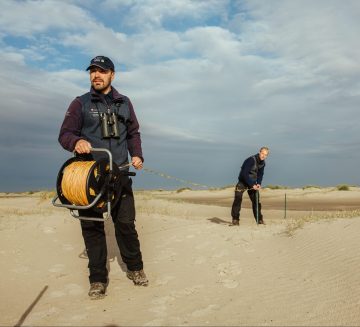 Zwei Nationalpark-Ranger beim Aufbau eines mobilen Zauns für den Strandbrüter-Schutz auf Borkum