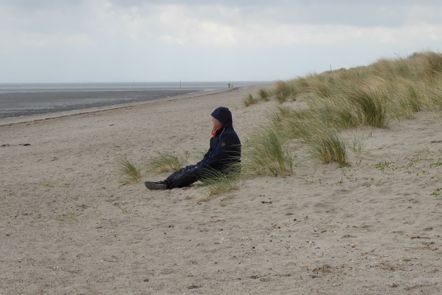 Person am Strand sitzend