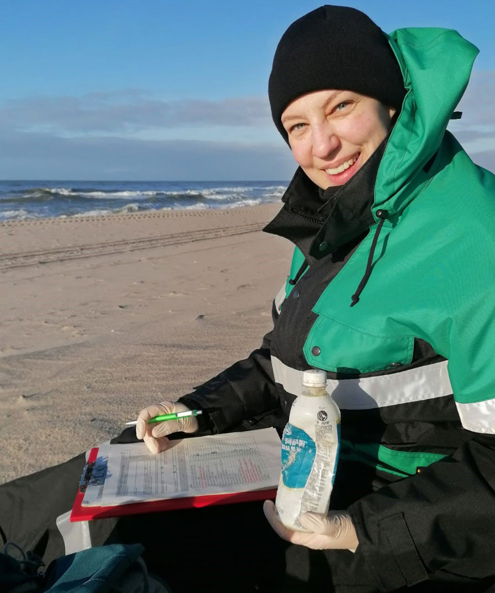 Frau dokumentiert am Strand Müll in einer Liste