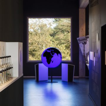 Flaschenpostregal mit Blick auf den Globus in der Ausstellung