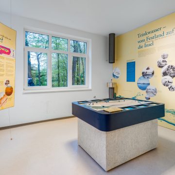 in der Mitte eines Raumes steht das Modell der Insel Wangerooge. An den Wänden hängen Infotafeln. In der Ecke steht ein Trinkbrunnen