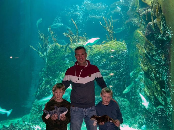 Erwachsener und zwei Kinder vor einem riesigen Aquarium.
